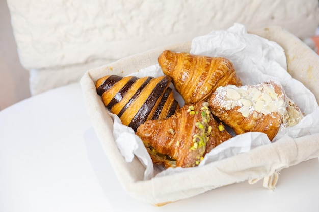 Un delizioso assortimento di croissant annidati in un cesto di vimini su un tavolo bianco