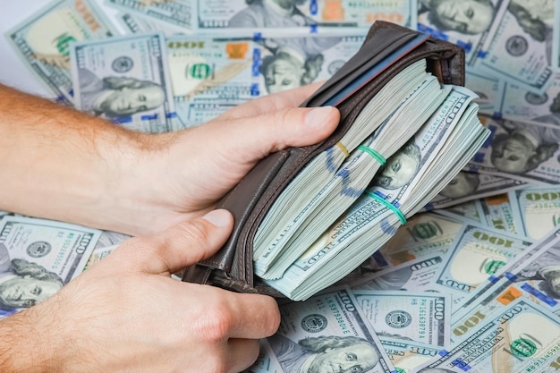 Un denaro in dollari nelle mani di un uomo d'affari in un portafoglio per un progetto di affari, viaggi e shopping