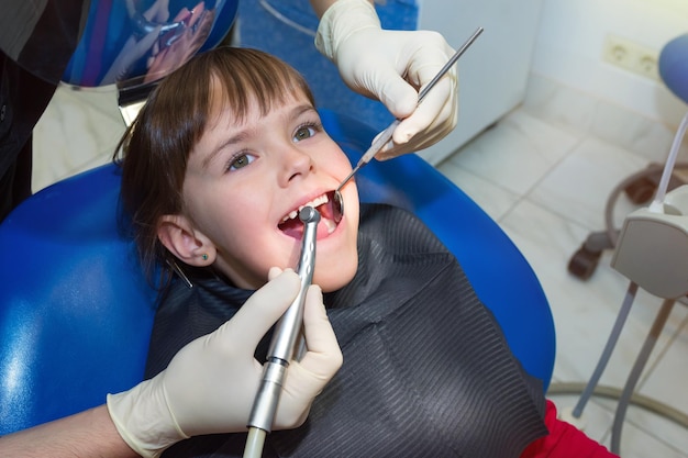 Un dentista che esamina i denti di un bambino in odontoiatria