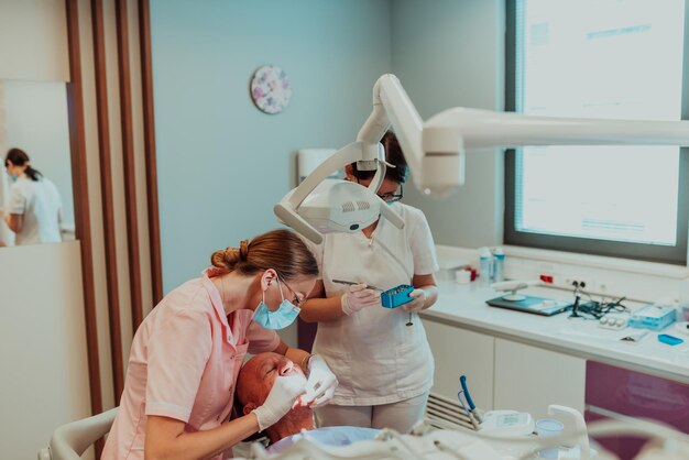 Un dentista con l'aiuto di un collega esegue un'operazione sulla mandibola di un paziente anziano in una moderna clinica odontoiatrica. Foto di alta qualità