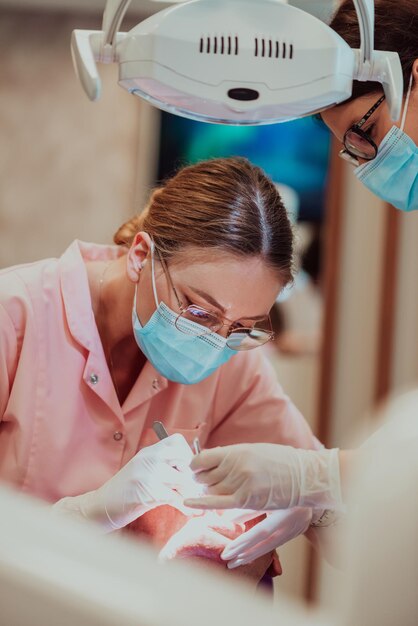 Un dentista con l'aiuto di un collega esegue un'operazione sulla mandibola di un paziente anziano in una moderna clinica odontoiatrica. Foto di alta qualità