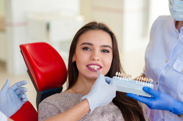 Un dentista con un assistente prende il colore per i denti della ragazza