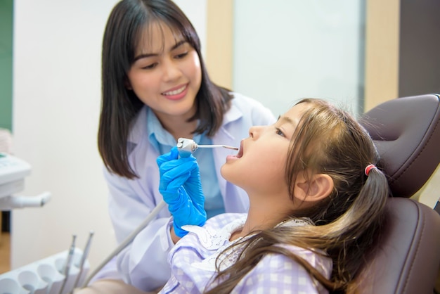 Un dentista femminile che dimostra come lavarsi i denti a una bambina in una clinica dentale