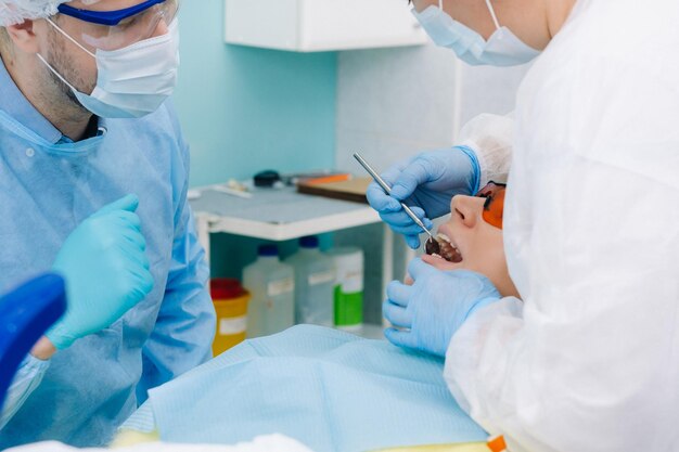 Un dentista maschio con strumenti dentali trapani i denti di un paziente con un assistente Il concetto di medicina odontoiatria e assistenza sanitaria