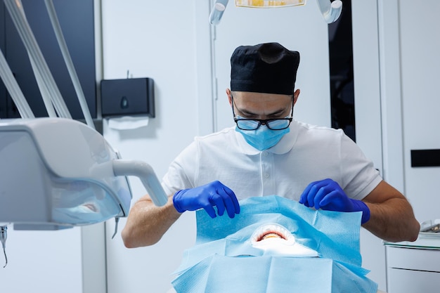 Un dentista professionista esamina i denti di un paziente con apparecchiature dentali e tiene gli strumenti dentali vicino alla bocca Dentista Cabina dentale