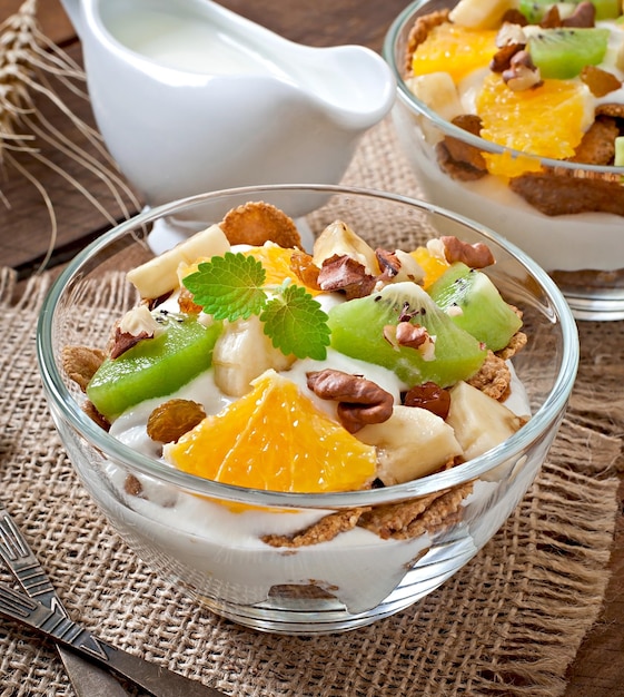 Un dessert sano con muesli e frutta in una ciotola di vetro sulla tavola