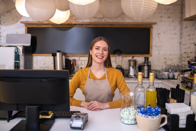 Un dipendente di caffè sorridente e allegro in attesa di clienti