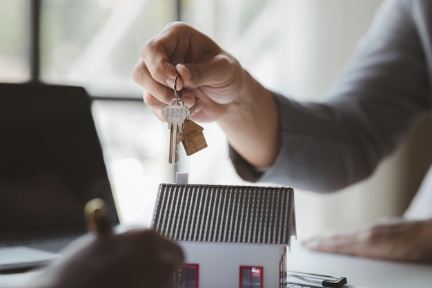Un dipendente di una società di noleggio di case consegna le chiavi di casa a un cliente che ha accettato di firmare un contratto di affitto spiegando i dettagli e i termini dell'affitto Idee per l'affitto di case e immobili