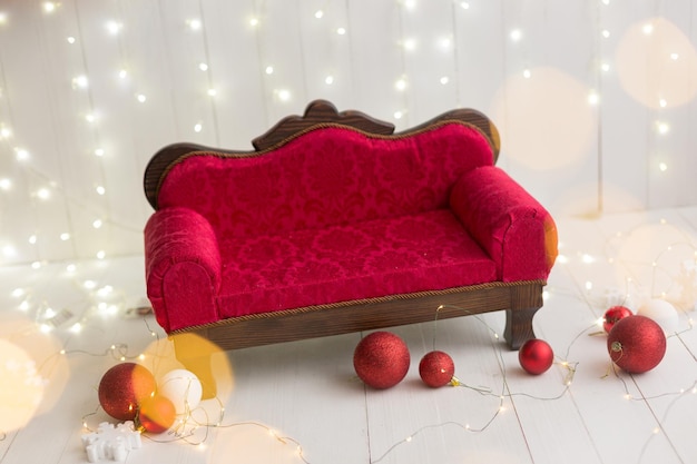 Un divano rosso con un cuscino rosso si trova su un pavimento bianco con decorazioni natalizie sul muro.