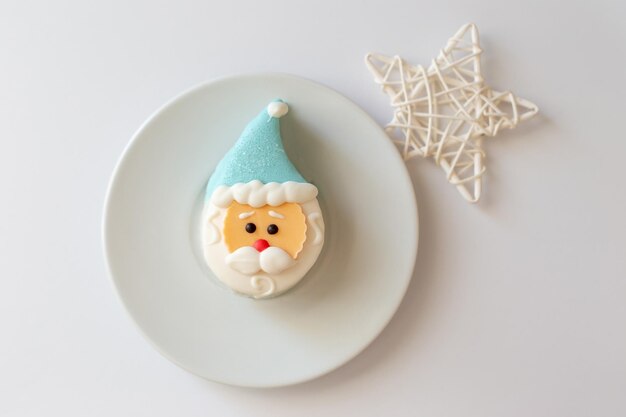 Un dolce dessert a forma di testa di Babbo Natale con un berretto blu giace su un piattino bianco