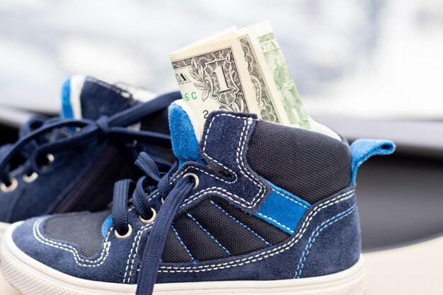 un dollaro in scarpe blu per bambini all'interno di un'auto moderna soldi come regalo