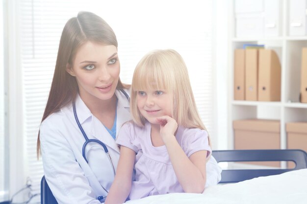 Un dottore e una bambina si siedono su una scrivania e guardano la telecamera.