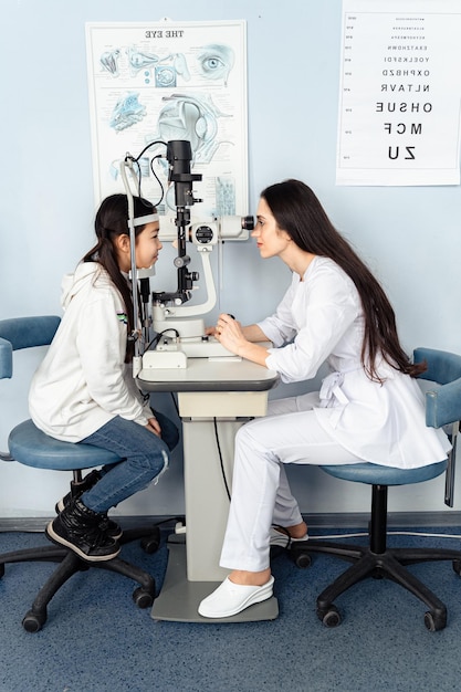 Un dottore e una ragazza stanno guardando un microscopio guarda un esame della vista con un dottore