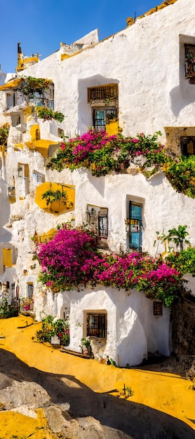 Un edificio bianco con fiori gialli e viola sul lato e la scritta "al mare" sul lato.