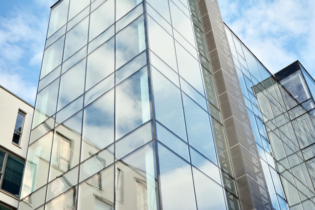 un edificio con una facciata in vetro e il cielo riflesso in essa