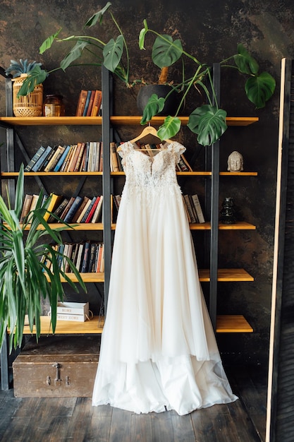 Un elegante abito da sposa in seta è appeso a una libreria.