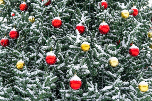 Un elegante albero di Natale decorato con palloncini rossi e dorati si trova nel parco sulla neve sciolta