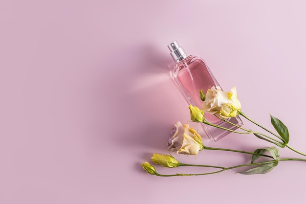 Un'elegante bottiglia di eau de parfum o spray cosmetico su uno sfondo pastello con fiori austoma primaverili Spazio vista dall'alto per il testo