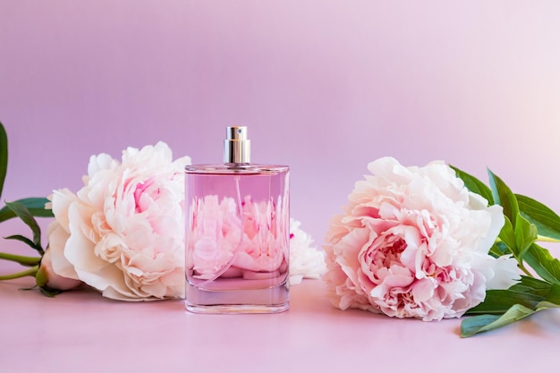 Un'elegante bottiglia di profumo fragrante sullo sfondo del delicato spazio di presentazione dell'aroma delle peonie da giardino per il testo