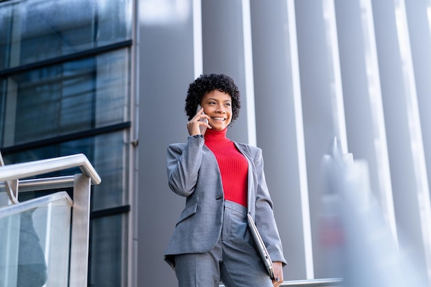 Un'elegante donna afroamericana che usa il telefono in un edificio per uffici al lavoro