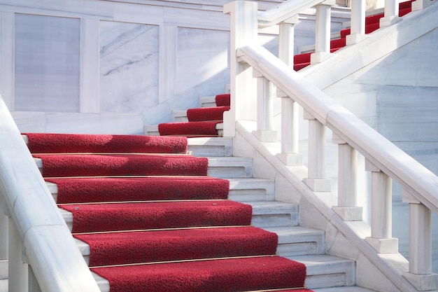 Un'elegante scala con tappeto rosso con bellissimi accenti di marmo bianco