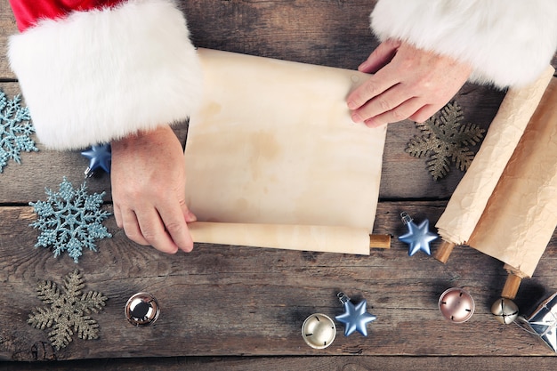 Un elenco di auguri di Natale nelle mani di Babbo Natale su un tavolo di legno