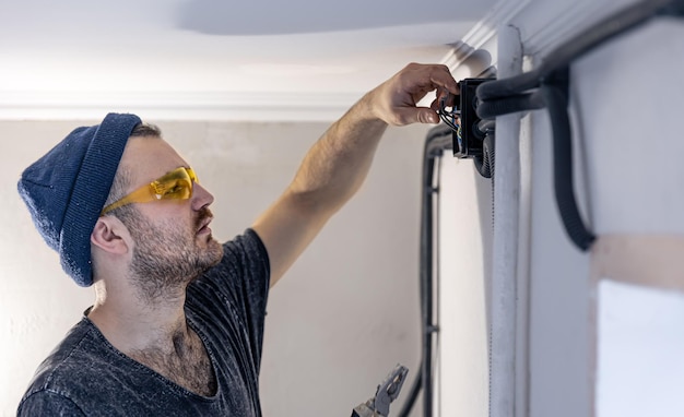 Un elettricista sta montando le prese elettriche sul muro bianco all'interno