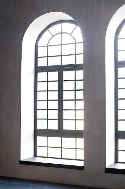 Un'enorme finestra sul pavimento dell'intero muro di cemento con un davanzale di legno. Loft industriale grunge interno.