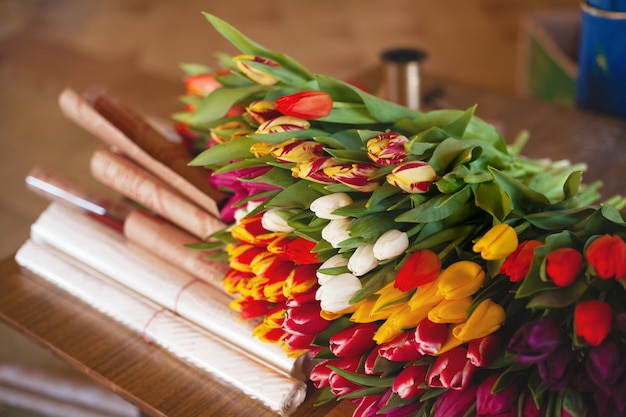 Un enorme mazzo multicolore di tulipani si trova su un tavolo in un negozio di fiori