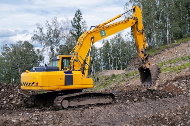 Un escavatore giallo lavora nelle montagne per la costruzione di strade