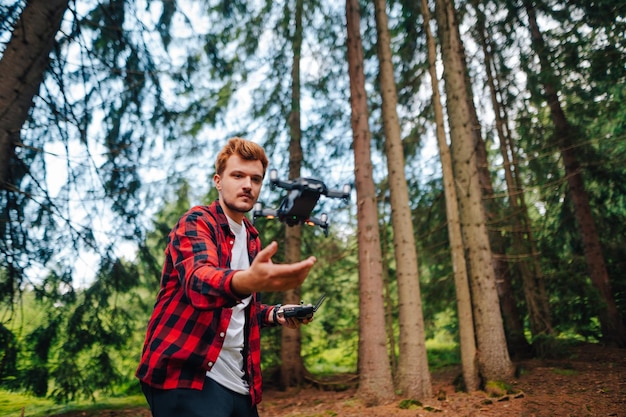 Un escursionista maschio lancia un drone dalla sua mano per girare un video in piedi in una foresta di montagna mentre cammina