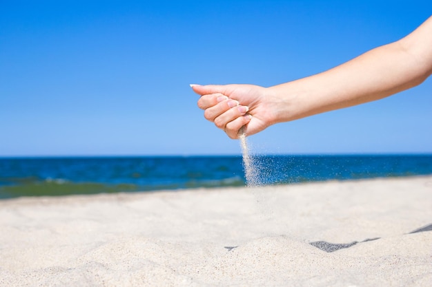 Un'estate alla moda del mare della sabbia delle belle mani sypyat sulla natura