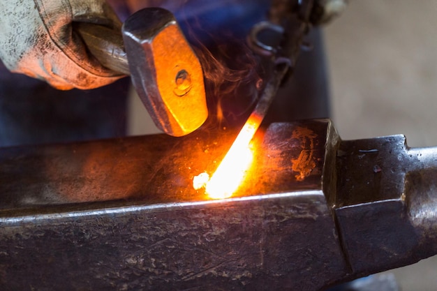 Un fabbro che forgia il ferro caldo sull'incudine.