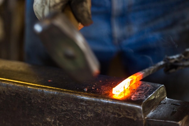 Un fabbro che forgia il ferro caldo sull'incudine.