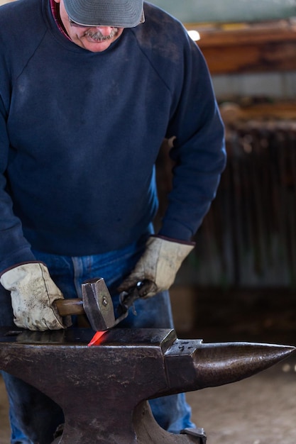 Un fabbro che forgia il ferro caldo sull'incudine.