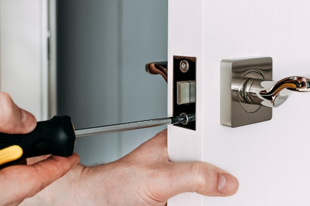 Un fabbro riparare la serratura della porta nella stanza Un fabbro che fissa la serratura con un cacciavite nero