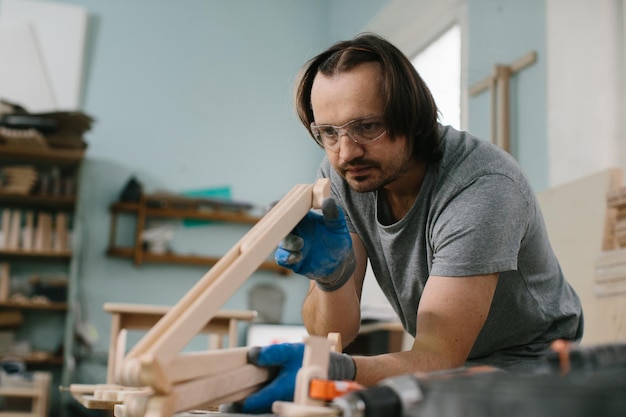 Un falegname fa giocattoli di legno in un laboratorio di falegnameria Realizzazione di una giostra da letto