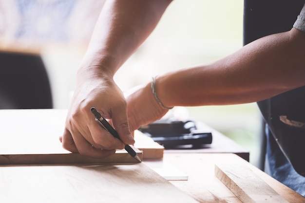 Un falegname misura le assi per assemblare le parti e costruire un tavolo di legno per il cliente