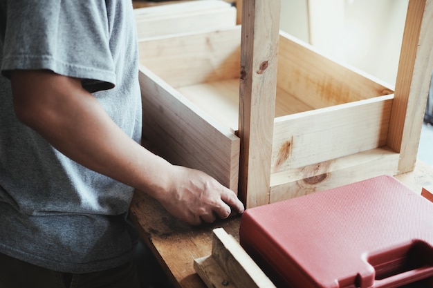 Un falegname misura le assi per assemblare le parti e costruisce un tavolo di legno per il cliente.