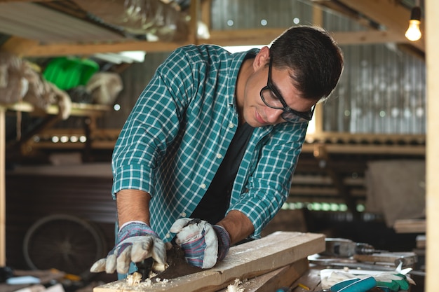 Un falegname spiana la piallatrice a mano in legno nell'officina domestica.