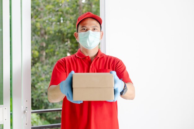 Un fattorino che indossa un vestito rosso tiene una cassetta dei pacchi.