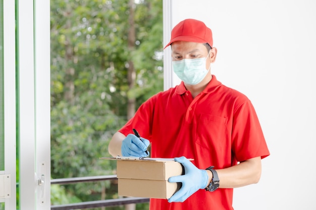 Un fattorino che indossa un vestito rosso tiene una cassetta dei pacchi.