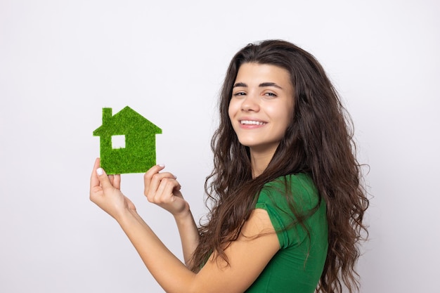 Un felice acquirente di casa Una giovane ragazza tiene in mano un modello di una casa verde Il concetto di verde