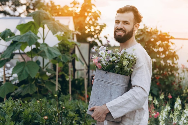 Un felice lavoratore in una piantagione di fiori che è impegnato nel suo lavoro preferito coltivando e curando i fiori, annaffia e taglia i fiori per i mazzi