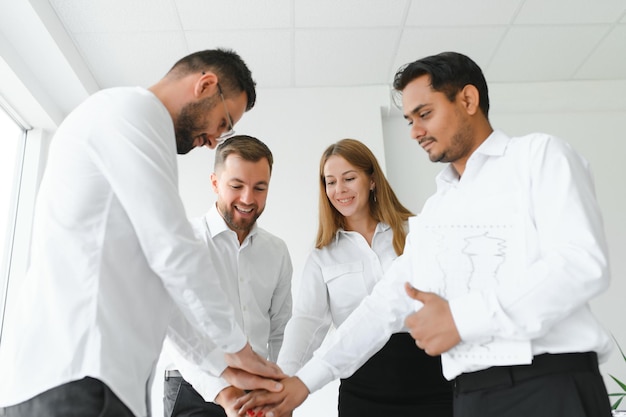 Un felice team di affari multirazziale di successo che dà il cinque mentre ridono e acclamano il loro successo