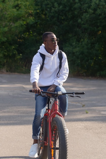 Un felice uomo afroamericano va in bicicletta attraverso un parco pubblico Ritratto Sport e tempo libero