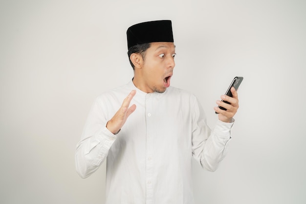 Un felice uomo musulmano asiatico sorridente in piedi con il gesto di saluto di Eid Mubarak e di benvenuto al Ramadan