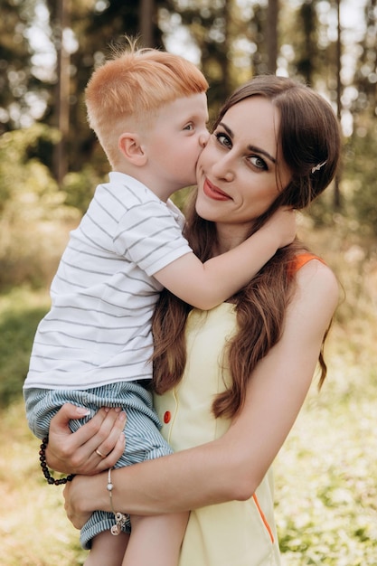 Un figlio dai capelli rossi bacia sua madre sulla guancia I valori della famiglia sono i più preziosi