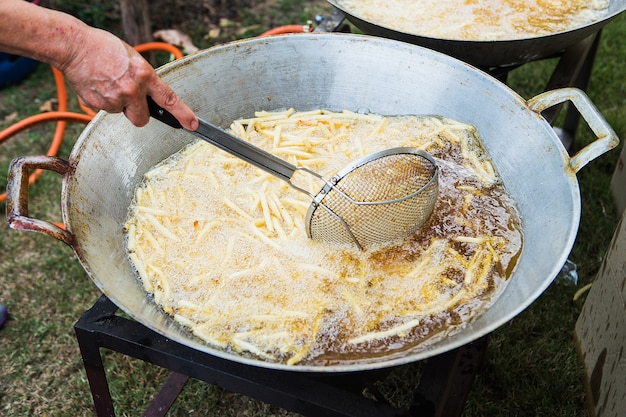 Un filtro pieno di patatine fritte viene abbassato nell&#39;olio bollente.