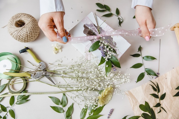 Un fioraio decora una confezione regalo con fiori e un nastro